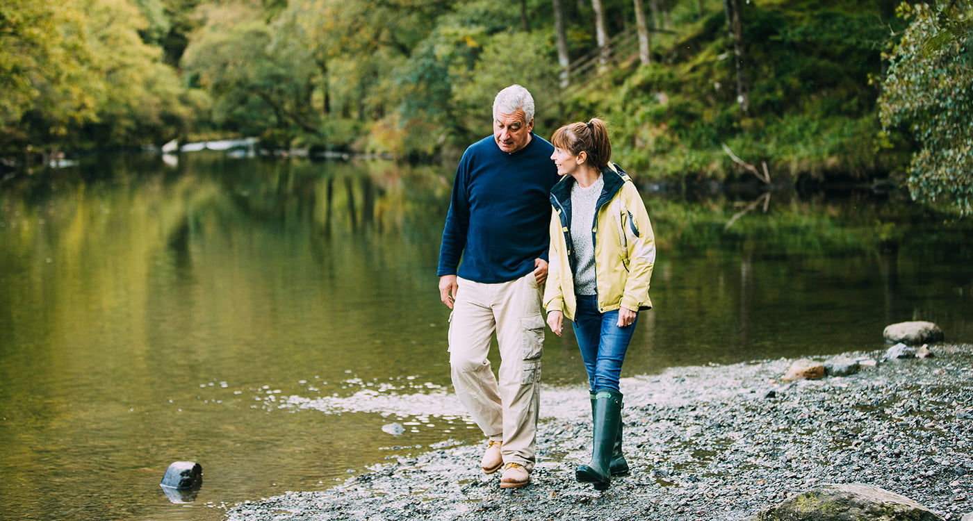 a woman and a man walking near water